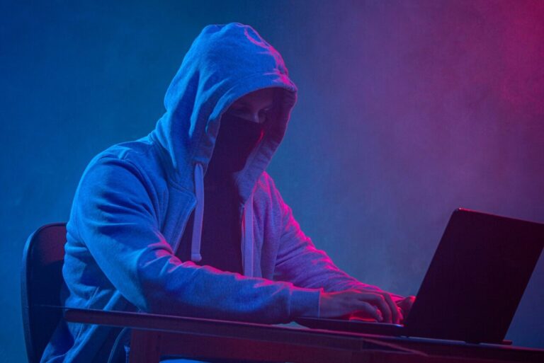 hooded-computer-hacker-stealing-information-with-laptop-scaled-e1673972345503